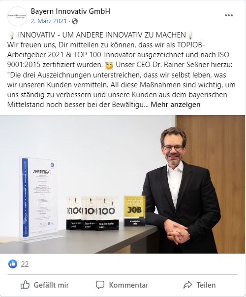 Facebook-Beitrag von Bayern Innovativ: Mann im Anzug neben der TOP JOB-Trophäe Arbeitgeber 2021 und weiteren Auszeichnungen
